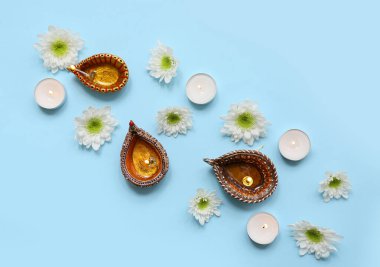 Çiçekli Diya lambaları ve mavi arka planda mumlar. Divaly kutlaması