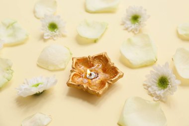 Sarı arka planda çiçek ve gül yapraklı Diya lambası. Divaly kutlaması