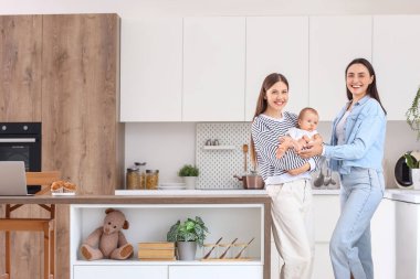 Mutfakta küçük bebekleri olan genç lezbiyen çift.