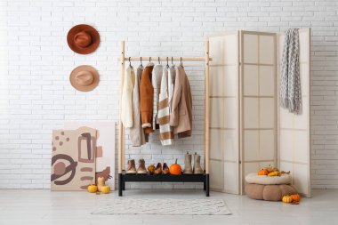 Koridorun içinde sonbahar kıyafetleri, katlanan ekran ve balkabakları var.