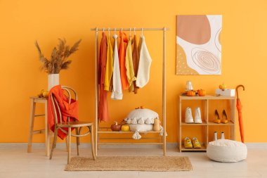 Sonbahar kıyafetleri, ayakkabıları ve balkabaklarıyla dolu bir oda.