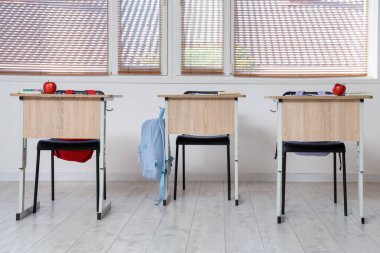 Boş sınıflarda not defterleri ve elmalarla okul sıraları.