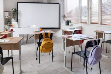 Okul sıraları ve projektör ekranlı sınıfın içi