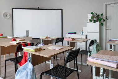 Okul sıraları ve projektör ekranlı sınıfın içi
