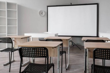 Okul sıraları ve projektör ekranlı sınıfın içi