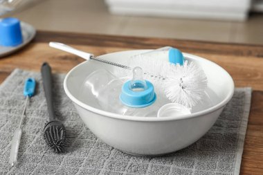 Mutfaktaki tezgahın üzerinde bebek şişeleri ve temizlik fırçalarıyla dolu bir havuz.