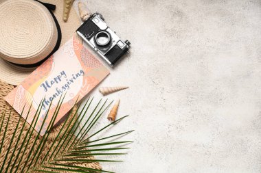 Şükran Günü için fotoğraf makinesi, şapka ve arka planda palmiye yaprağı olan bir kart.