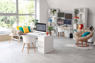 Masaları, raf üniteleri ve kanepesi olan ışık programcıları ofisinin içinde.