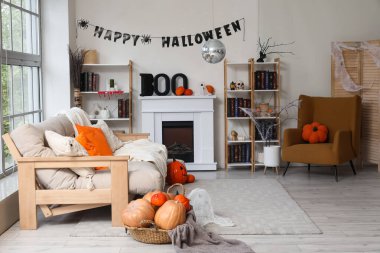 Cadılar Bayramı için dekore edilmiş oturma odasının içi kanepe, disko topu, şömine ve balkabaklarıyla süslenmiş.