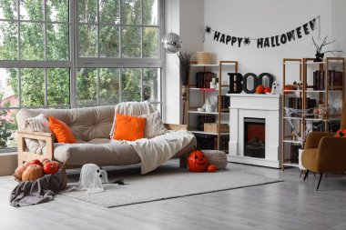 Cadılar Bayramı için dekore edilmiş oturma odasının içi kanepe, disko topu, şömine ve balkabaklarıyla süslenmiş.