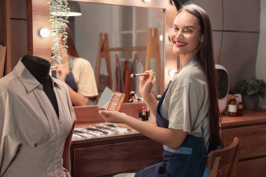 Geceleri soyunma odasında fırça ve göz farı olan kadın makyaj sanatçısı.