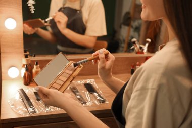 Geceleri soyunma odasında fırça ve göz farı olan kadın makyaj sanatçısı.