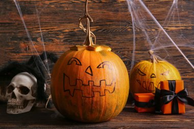 Cadılar Bayramı balkabakları hediye kutuları ve kahverengi ahşap arka planda süslemeler