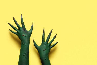 Sarı arka planda pençeleri olan cadının yeşil elleri. Cadılar Bayramı