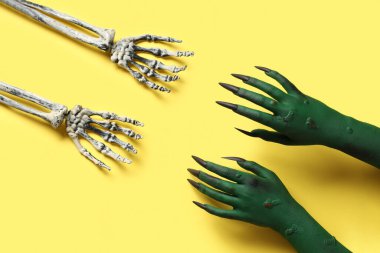 İskelet ve yeşil cadının elleri sarı arkaplanda. Cadılar Bayramı