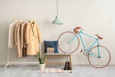 Koridorun iç tarafında sonbahar kıyafetleri, bank ve bisikletle dizilin.