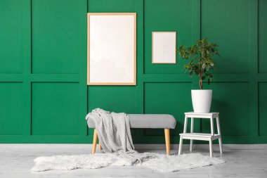 Yeşil duvarın yanındaki tezgah, çerçeve ve bitki.