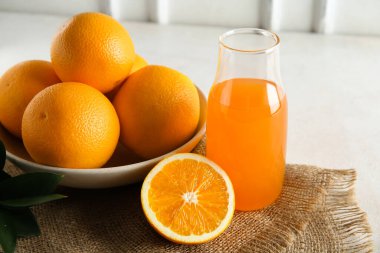 Bir şişe taze portakal suyu ve beyaz arka planda meyveler.