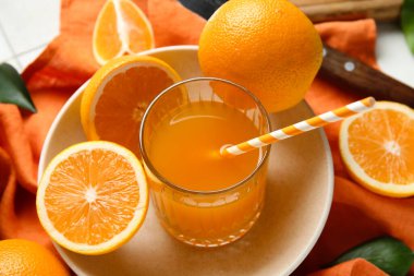 Beyaz fayanslı bir bardak taze portakal suyu ve tabak.