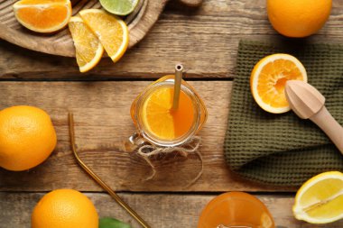 Mason kavanozu taze portakal suyu, farklı narenciye meyveleri ve tahta arka planda meyve sıkacağı.