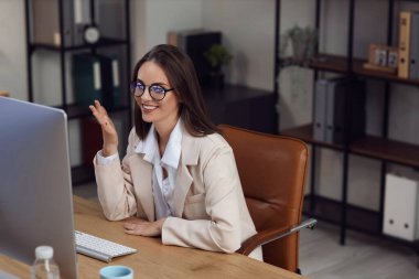 Genç iş kadını gece ofiste görüntülü sohbet yapıyor.