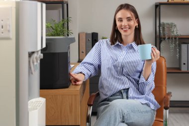 Ofisteki masasında kahve fincanı ve taşınabilir güneş istasyonu olan genç bir kadın.