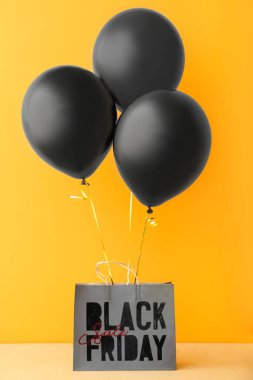 Sarı arka planda balonlar ve alışveriş çantası. Kara Cuma indirimi