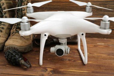 Modern kuadkopter, askeri botlar ve tahta arka planda el bombası.