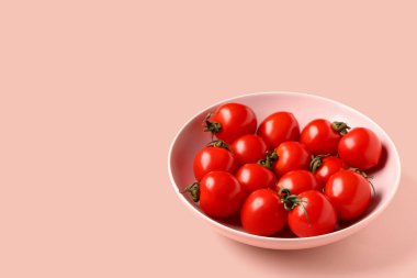 Pembe arka planda taze kiraz domatesli kase.