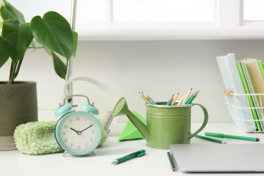 Laptop ve kırtasiyeli modern okul masası beyaz duvarın yanında.