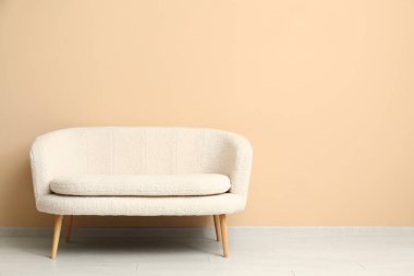 Bej duvarın yanındaki rahat beyaz kanepe.