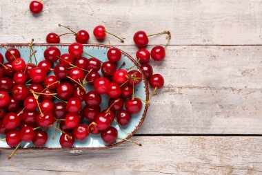 Gri ahşap arka planda kırmızı kirazlı