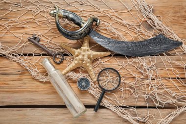 Parşömenli korsan kılıcı, büyüteç, pusula ve ağ kahverengi ahşap arka planda