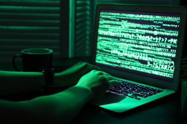 Kadın programcı gece ofiste dizüstü bilgisayarda daktilo kullanıyor.