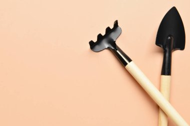 Bej arka planda bahçe tırmığı ve kürek.