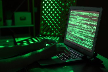 Kadın programcı gece ofiste dizüstü bilgisayarda daktilo kullanıyor.