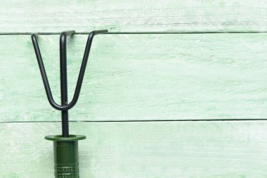 Yeşil ahşap arka planda bahçe tırmığı.