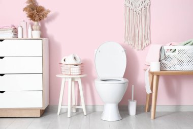 Seramik klozet ve kağıt rulolarla modern tuvaletin şık bir iç mekanı.