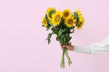 Young woman with beautiful sunflowers on pink background