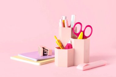 Pembe arka planda farklı kırtasiye malzemesi olan tutucu