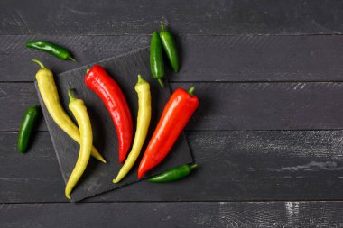 Siyah ahşap arka planda farklı taze kırmızı biberli tahta.