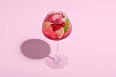 Pembe arka planda bir bardak taze ahududu mojito.