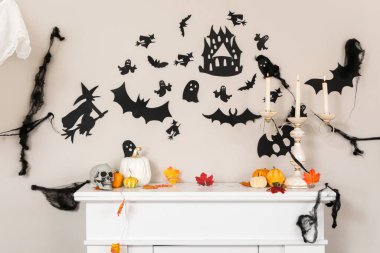 Balkabaklı şömine rafı, dökülen yapraklar, mumlar ve Cadılar Bayramı dekoru oturma odasında.