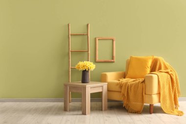 Ekoseli rahat koltuk ve oturma odasında nergis çiçekleri olan kahve masası.