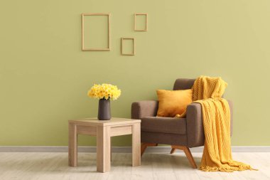 Kareli rahat bir koltuk ve oturma odasında nergis çiçekleri olan kahve masası.