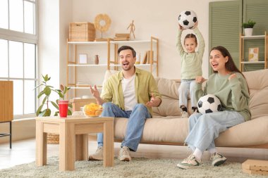 Evde futbol maçı izleyen mutlu bir aile.
