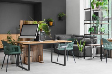 Masası, rüzgar türbini modeli ve bitkileri olan mühendislik bürosu.