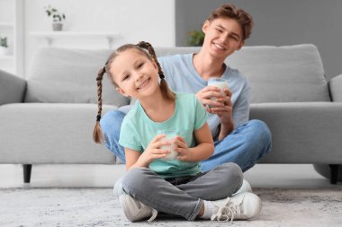 Küçük kız ve babası süt bardaklarıyla evde oturuyorlar.