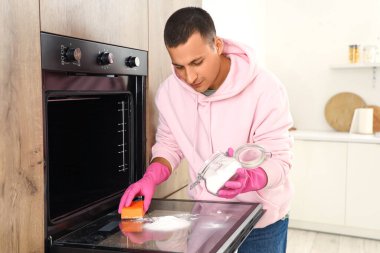 Mutfakta gazoz ve sünger fırını olan genç bir adam var.