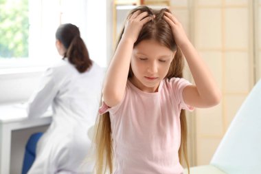 Pedikülozu olan küçük bir kız klinikte kaşınıyor.